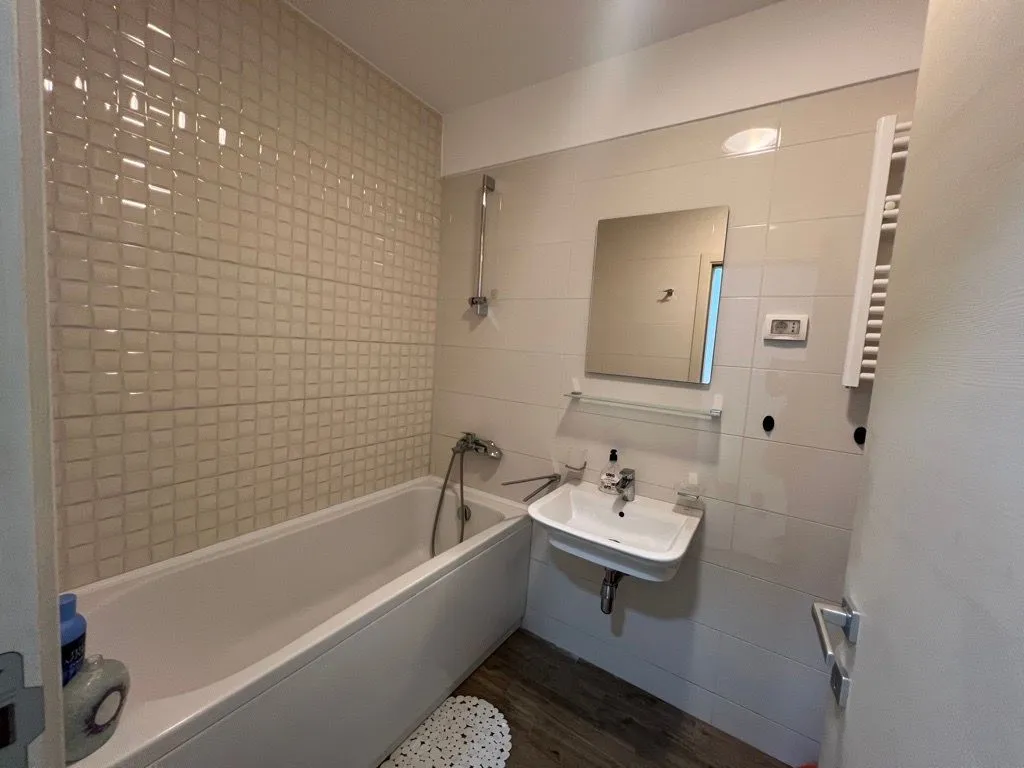 Small bathroom with a bathtub, washbasin, and mirror.