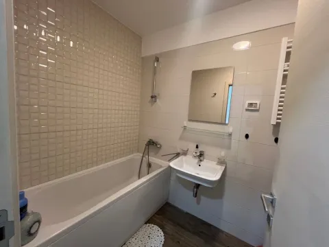 Small bathroom with a bathtub, washbasin, and mirror. - image 7