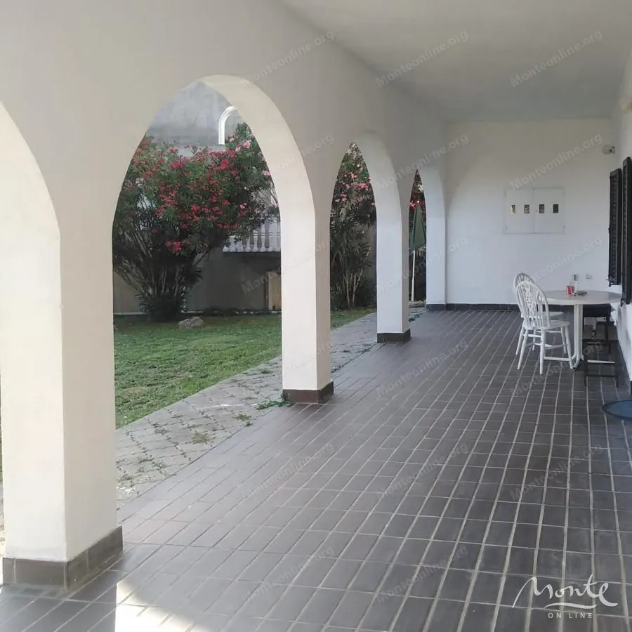 Covered terrace with tiled flooring and arches overlooking the yard.