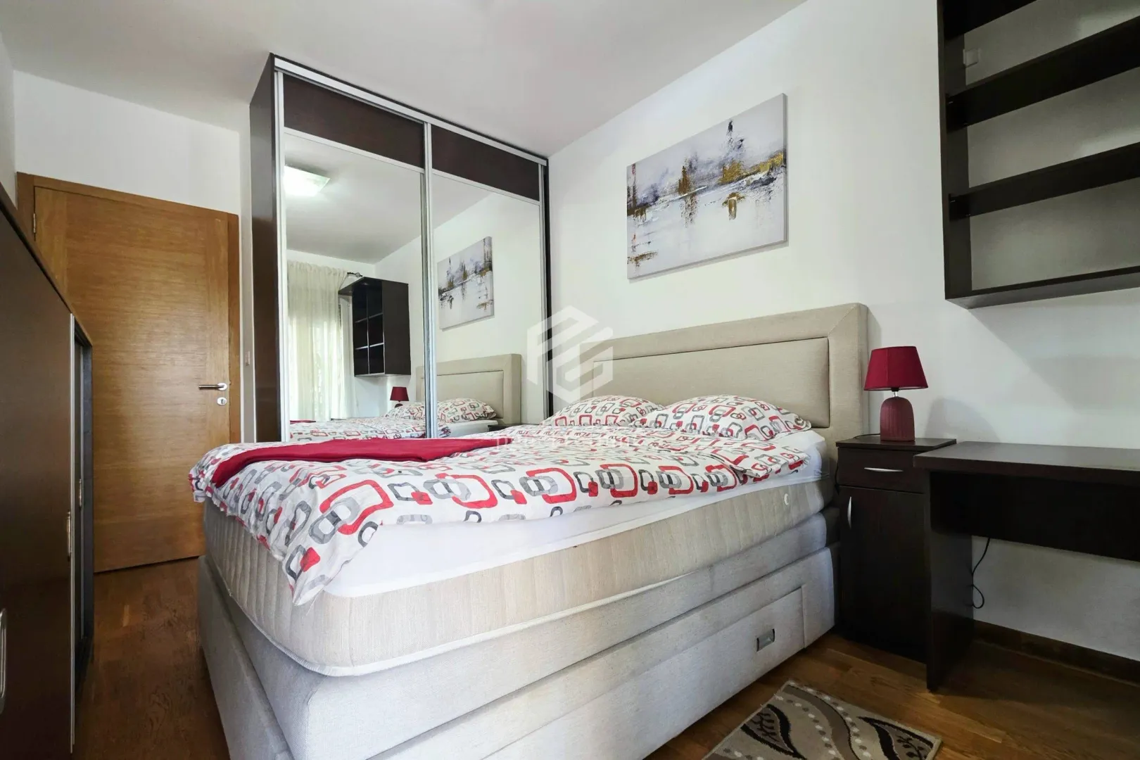 Furnished bedroom with a double bed and a mirrored built-in wardrobe.