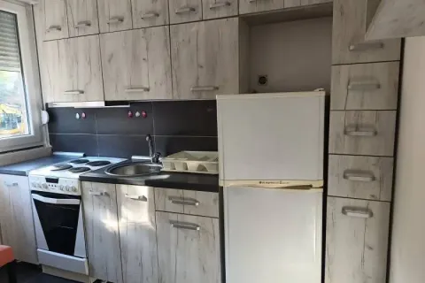 Small kitchen with wooden cabinets, stove, and refrigerator. - image 2