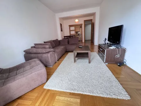 Spacious living room with a sectional sofa, rug, and TV unit. - image 2