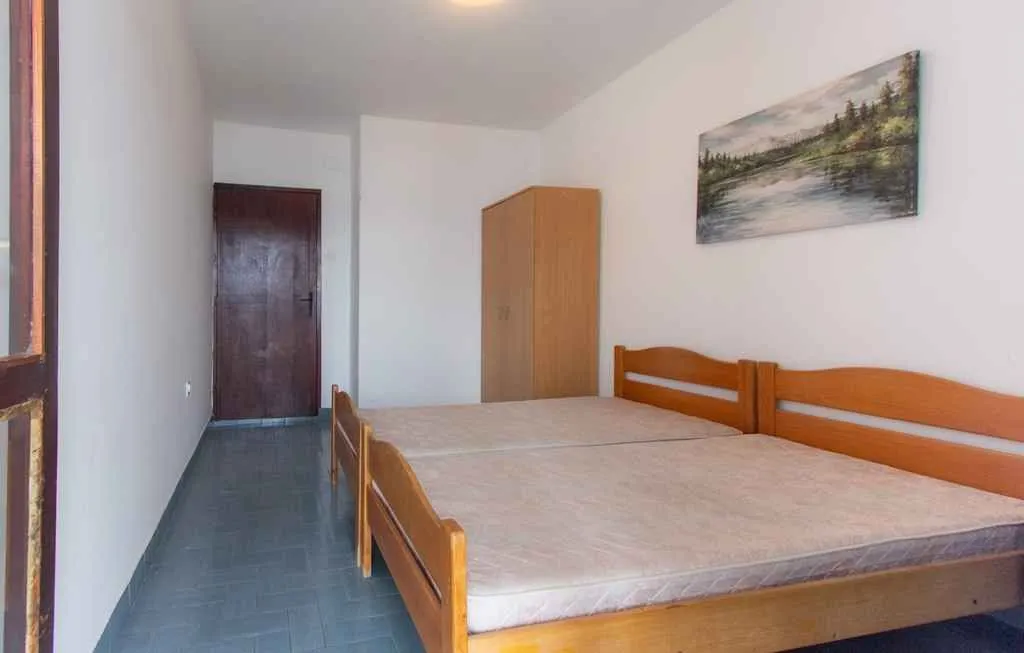Spavaća soba sa dva drvena kreveta i ormarom.