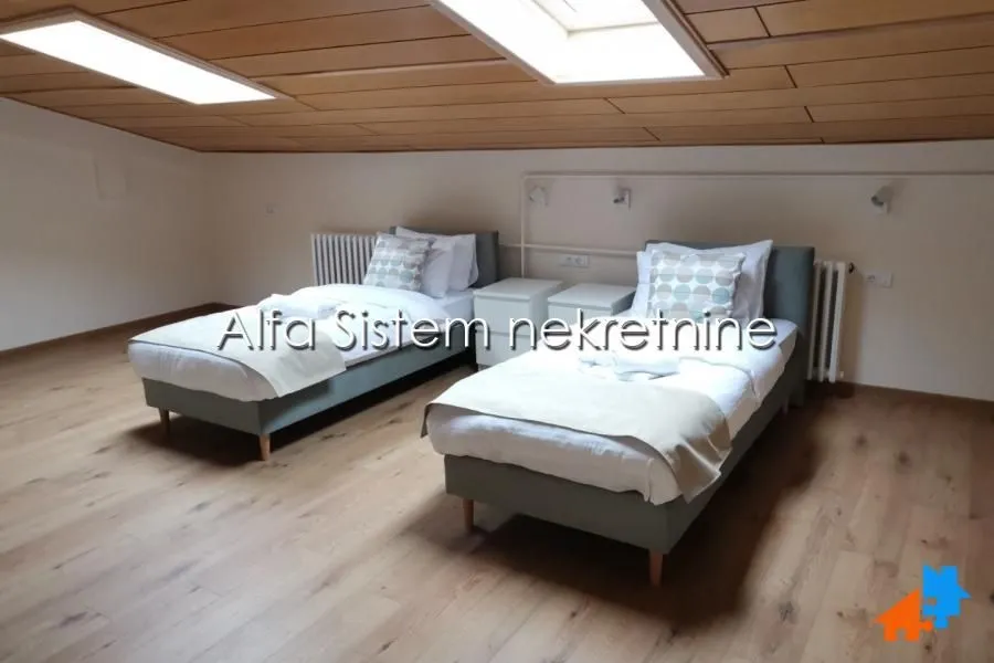 Potkrovlje opremljeno sa dva odvojena kreveta i drvenim plafonom.