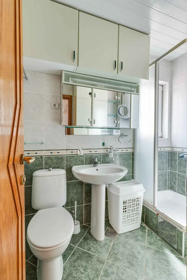 Smaller bathroom with a shower cabin, washbasin, and toilet.