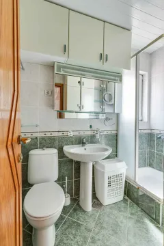 Smaller bathroom with a shower cabin, washbasin, and toilet. - image 15