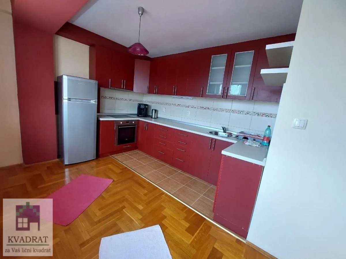 Kitchen with red cabinets, a refrigerator, and a wooden floor.