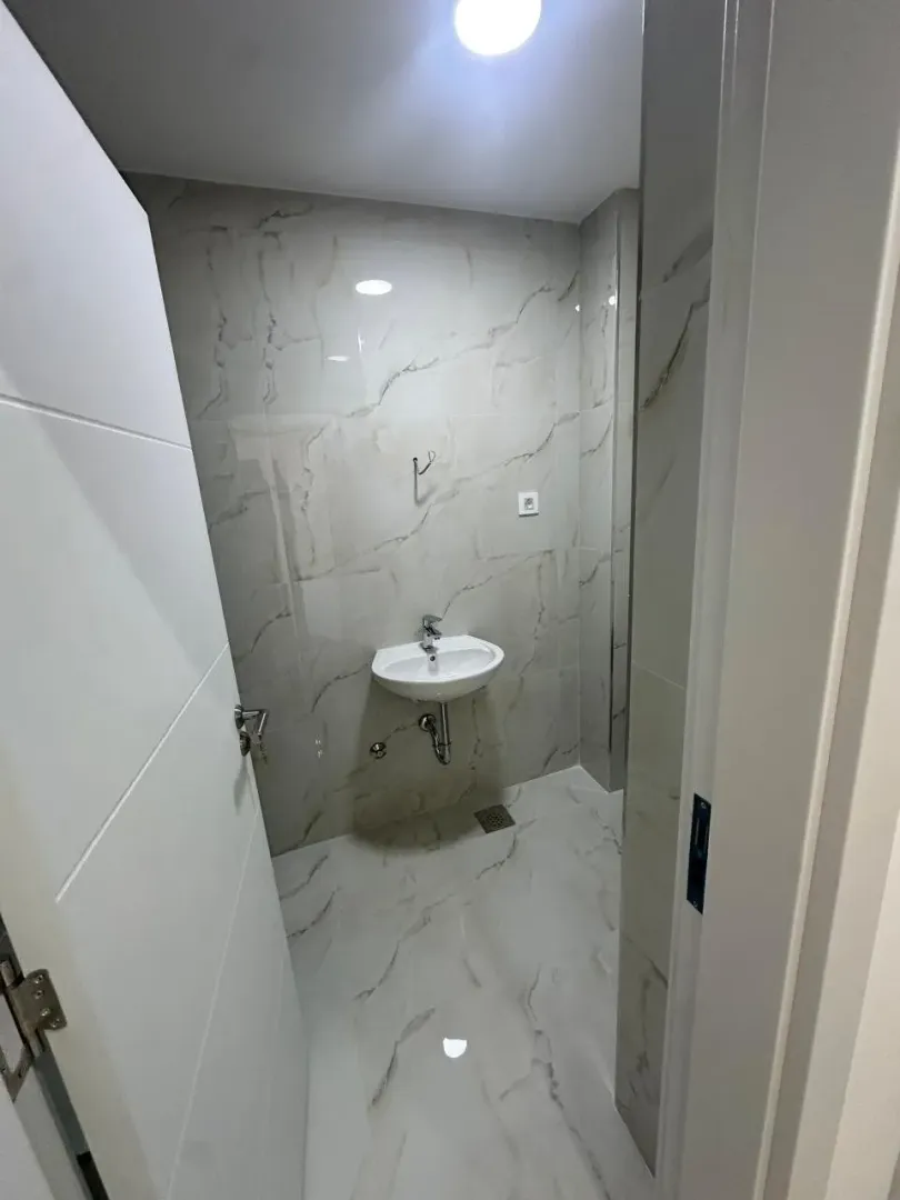Small bathroom lined with marble tiles featuring a washbasin.