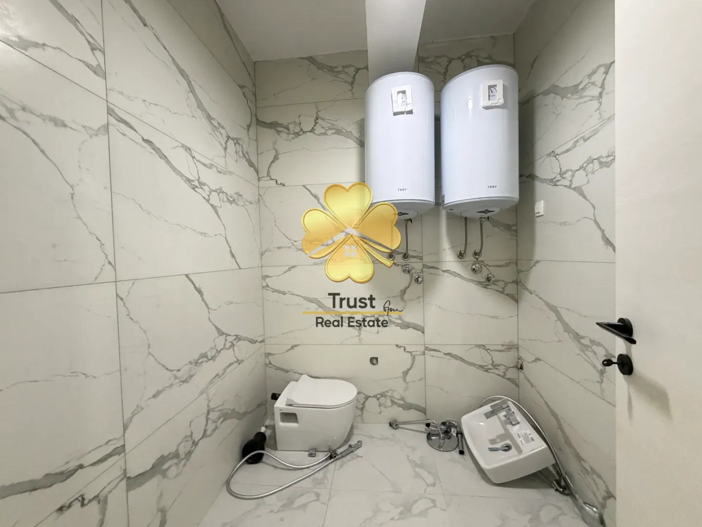 Unfinished bathroom with sanitary ware being installed and two water heaters.