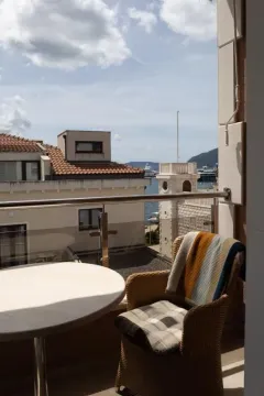Namješten balkon sa stolom i foteljom sa pogledom na more i okolne objekte. - image 8