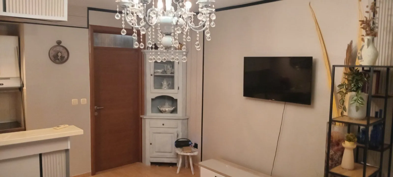 Dnevna soba sa TV-om, lusterom i drvenim namještajem.