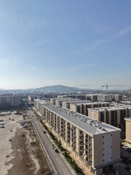 Pogled sa visine na gradski pejzaž sa zgradama i okolnim brdima. - image 15