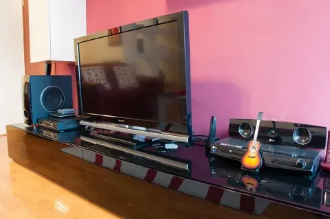 Living room with a television on a media console and a pink wall. - image 3