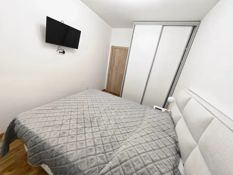 Namještena spavaća soba sa bračnim krevetom, plakarom i televizorom na zidu. - image 9