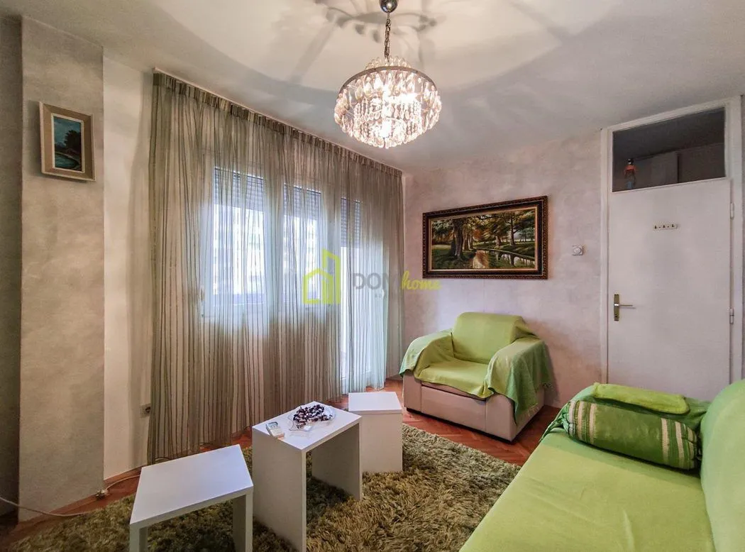 Dnevna soba sa garniturom, stočićima i lusterom.
