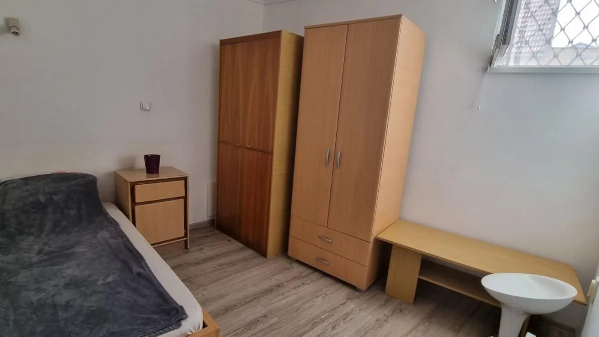 Nameštena spavaća soba sa krevetom, ormarima i noćnim stočićem.