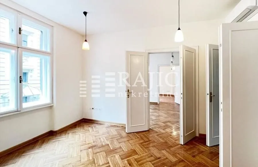Empty room with parquet flooring and white wooden doors.