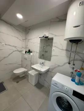 Kupatilo opremljeno sanitarijama, umivaonikom, ogledalom i veš mašinom. - image 4