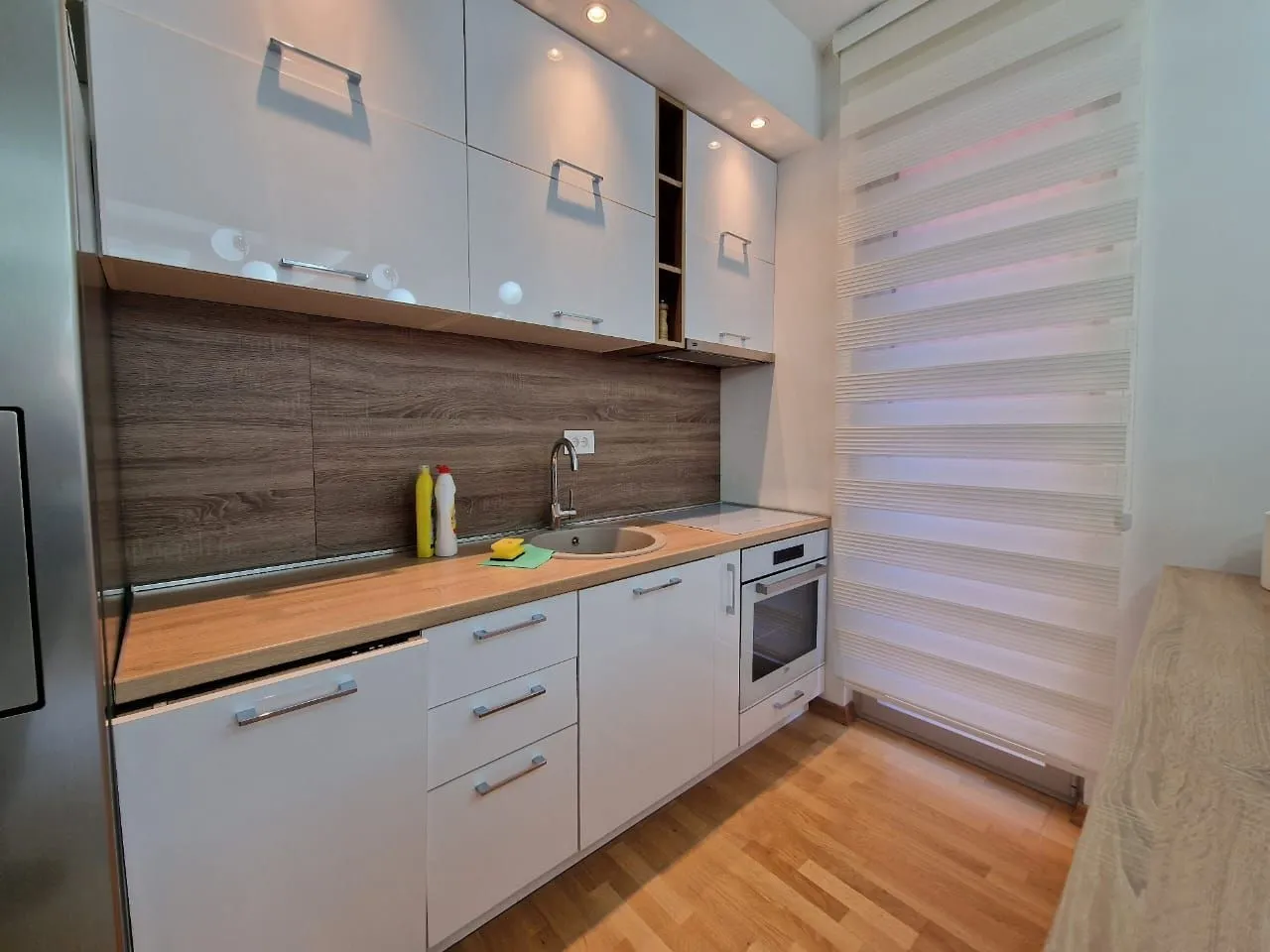 Modern kitchen with white cabinetry and a wooden countertops.
