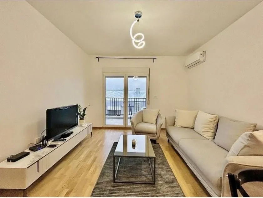 Bright living room with a sofa, TV, and access to the terrace.