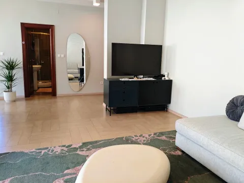 Dnevna soba sa garniturom, TV komodom i ogledalom na zidu. - image 8