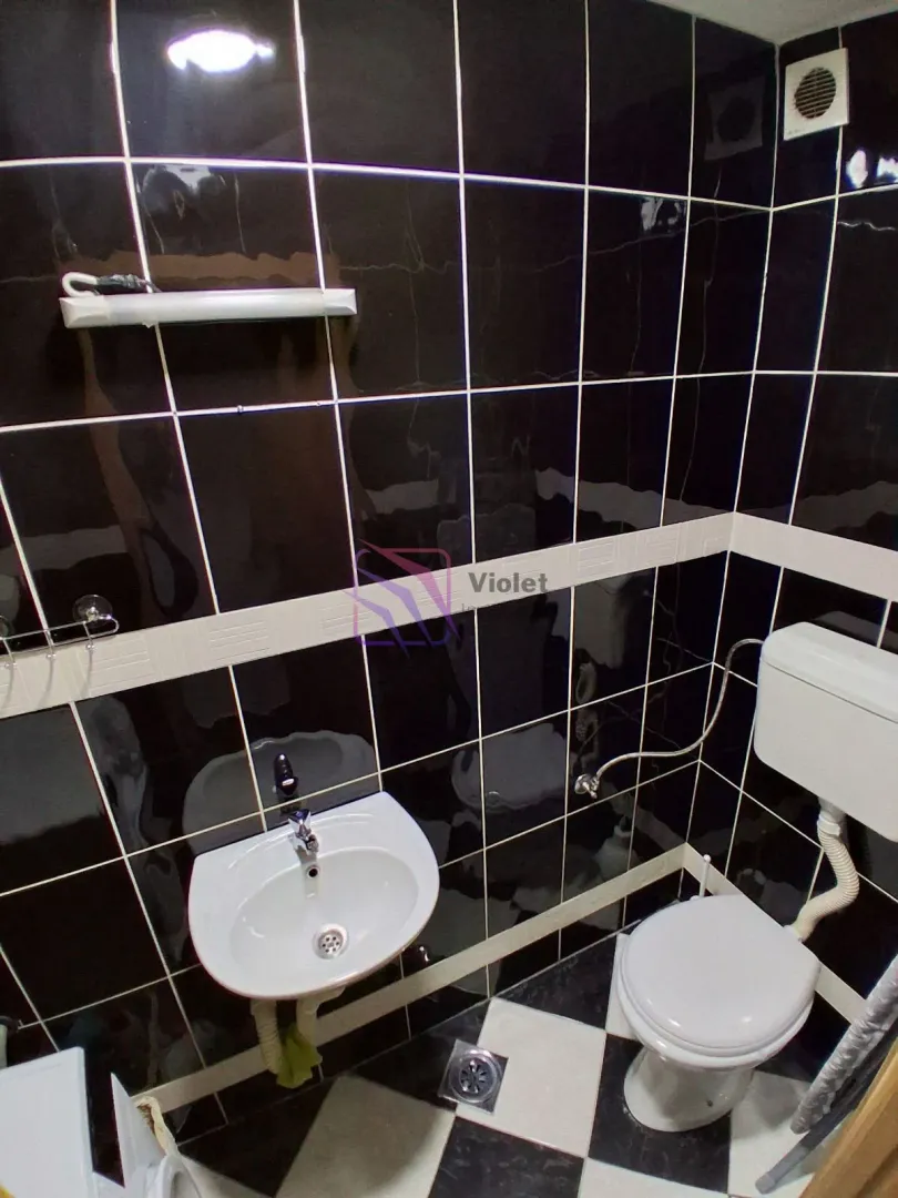 Manje kupatilo obloženo crnim i bijelim pločicama sa umivaonikom i wc šoljom.