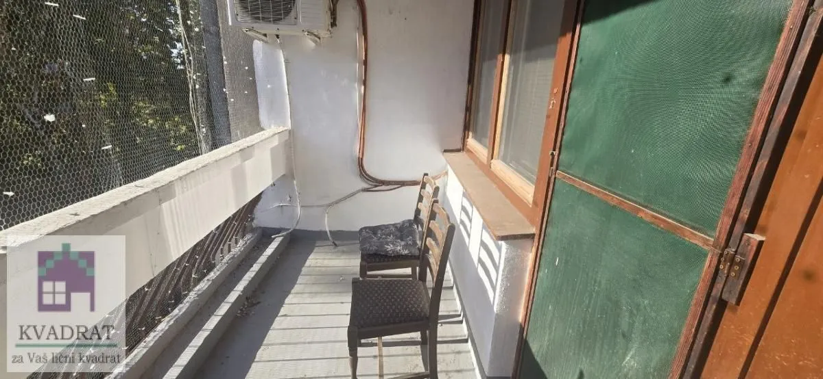 Dugačka spoljna terasa sa stolicama i mrežom za zaštitu.