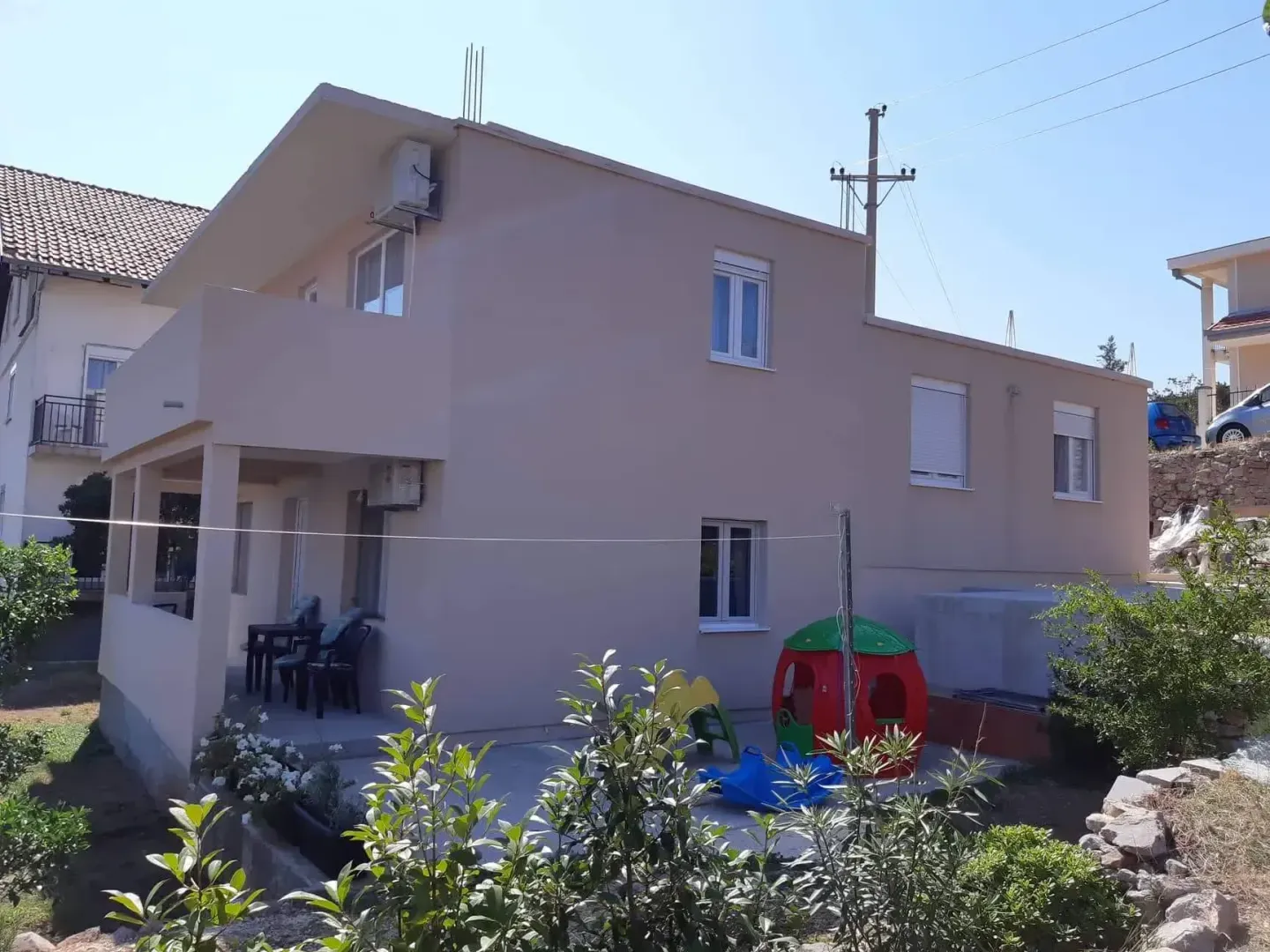 Pogled na spoljašnjost kuće sa dvorištem i terasom.