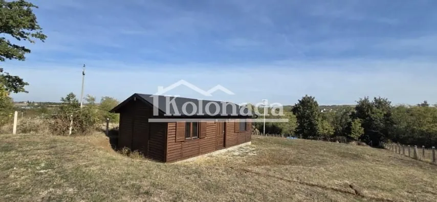 Pogled na drvenu kuću u prirodi sa travnatim dvorištem.