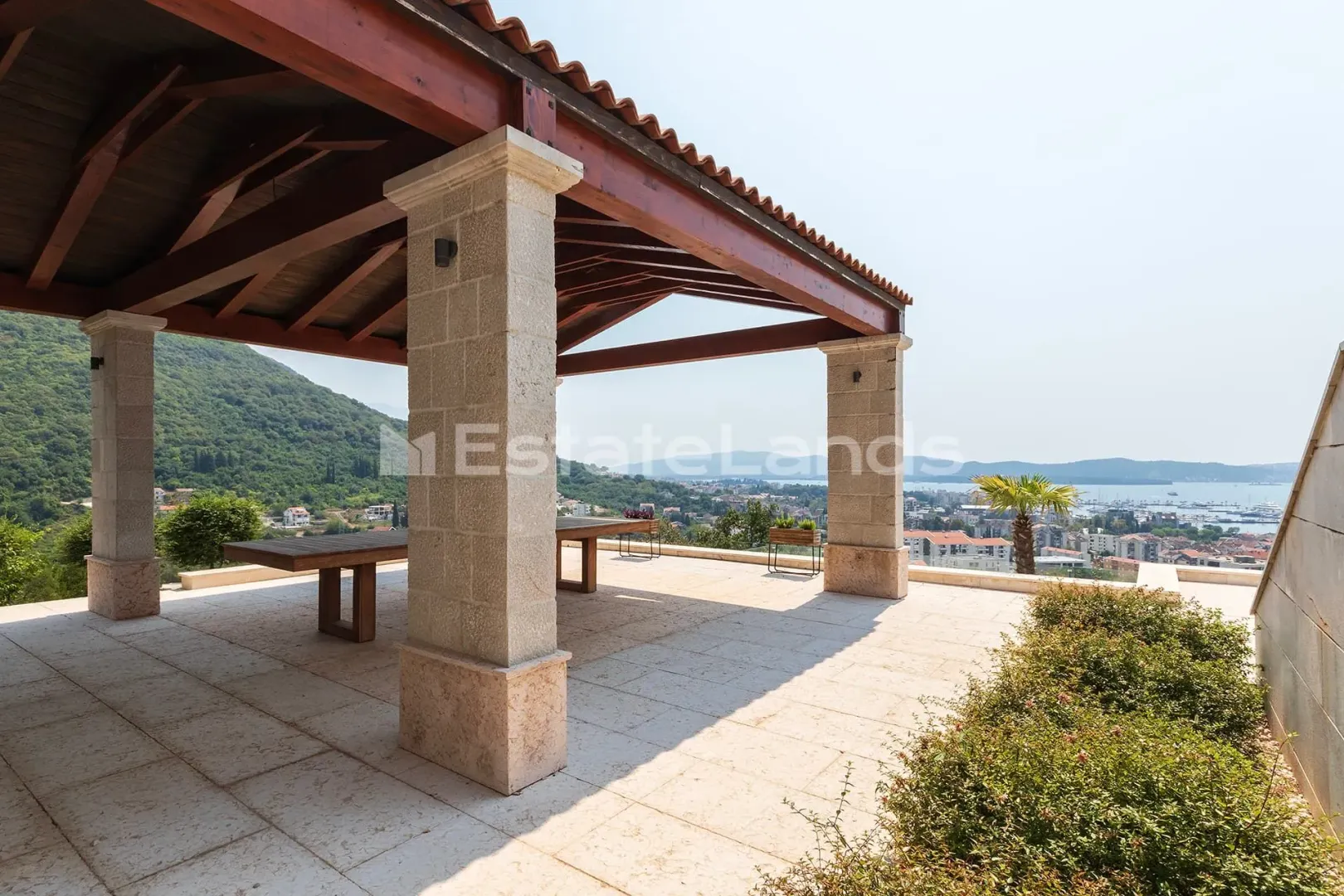 Natkrivena terasa sa kamenim stubovima i pogledom na more.