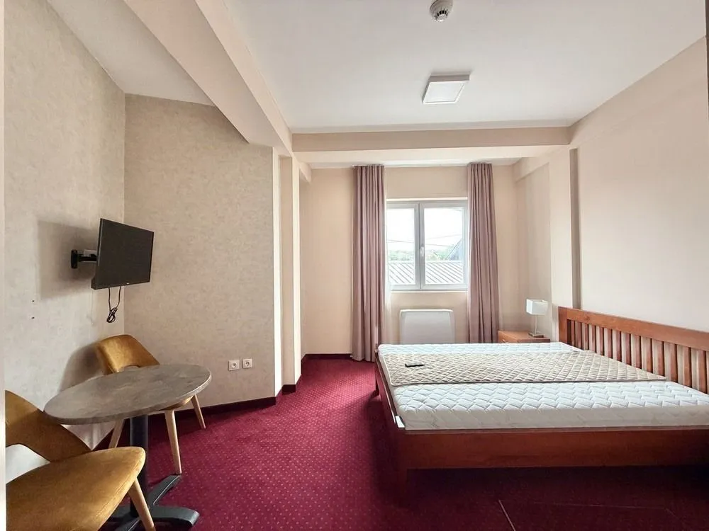 Spacious bedroom with a double bed, a table, and natural light.