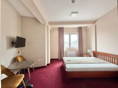 Spacious bedroom with a double bed, a table, and natural light. - image 11
