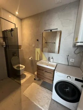 Modern bathroom with a walk-in shower, washbasin, and washing machine. - image 8