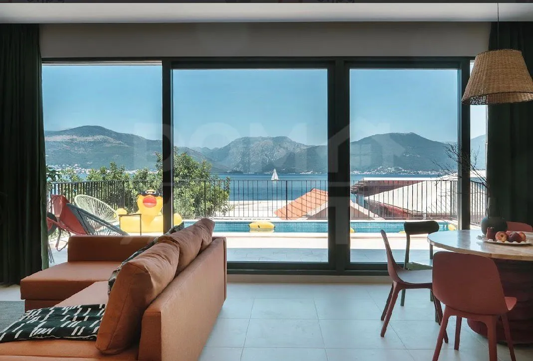 Living room with dining area and a view of the sea and pool.