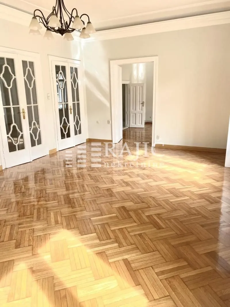 Empty room with parquet flooring and white doors.