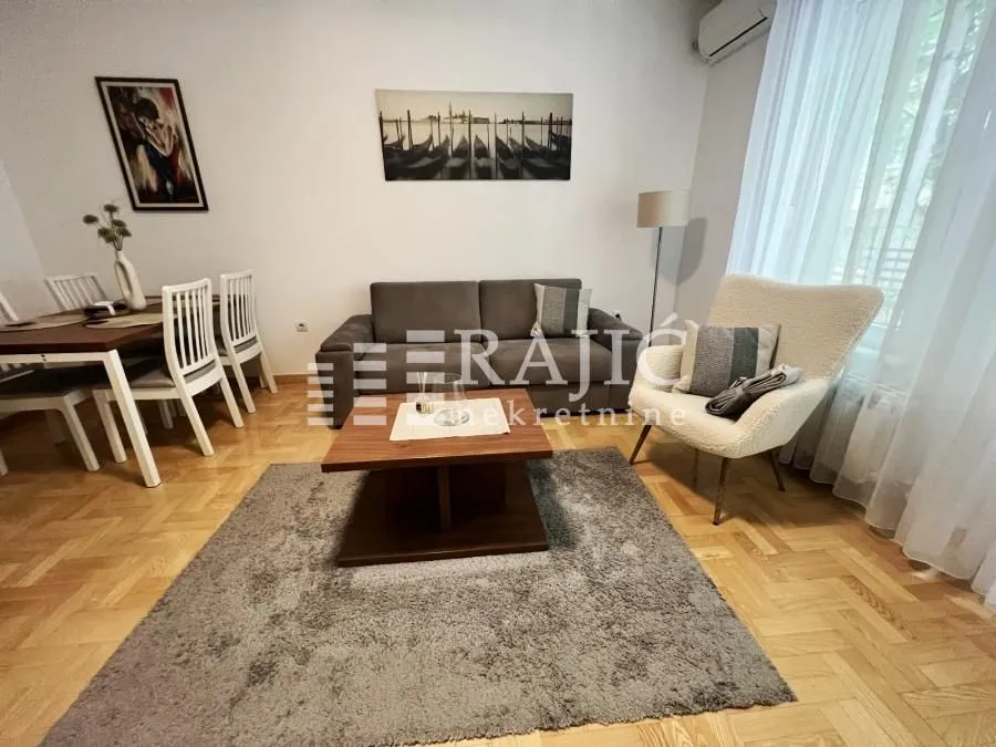 Spacious living room with sofa, armchair and dining area.