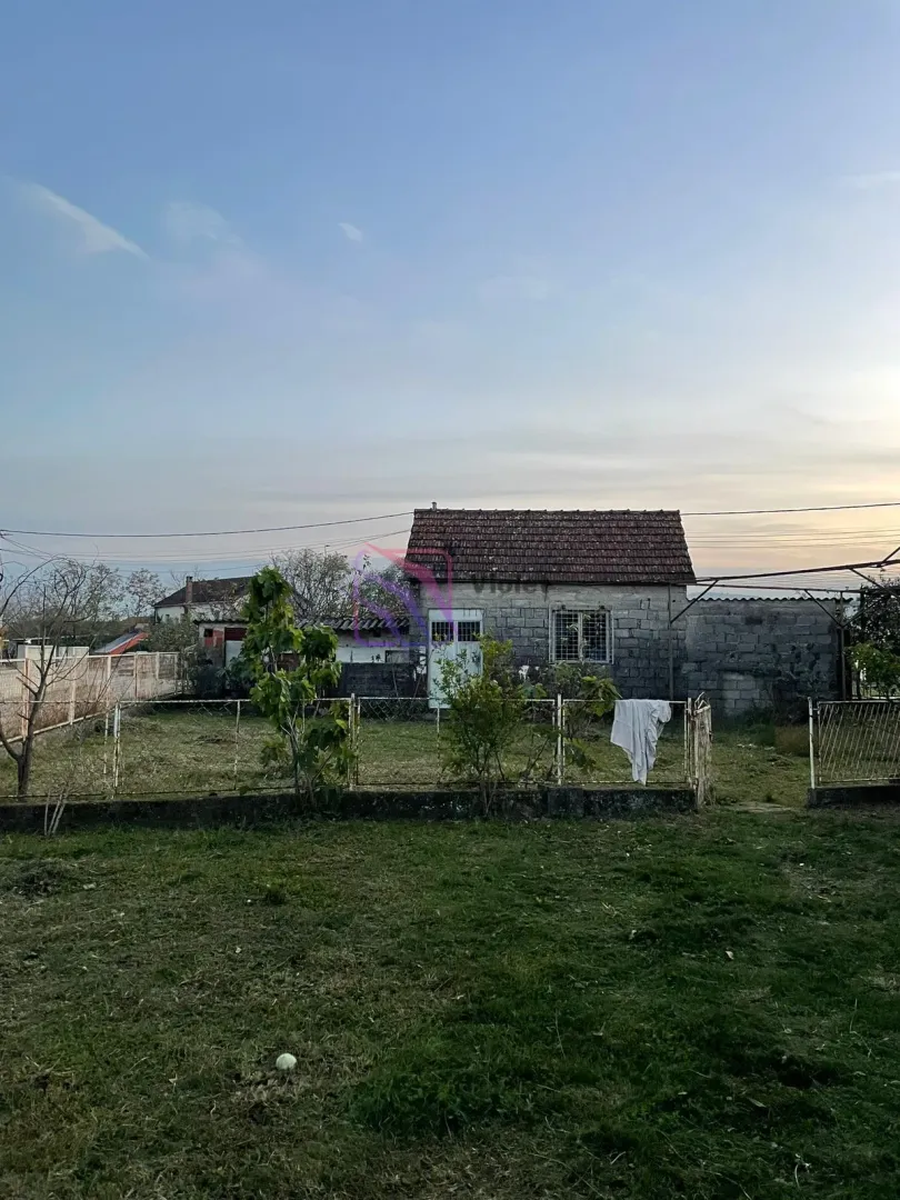 Pogled na stariju prizemnu kuću sa dvorištem i ogradom.