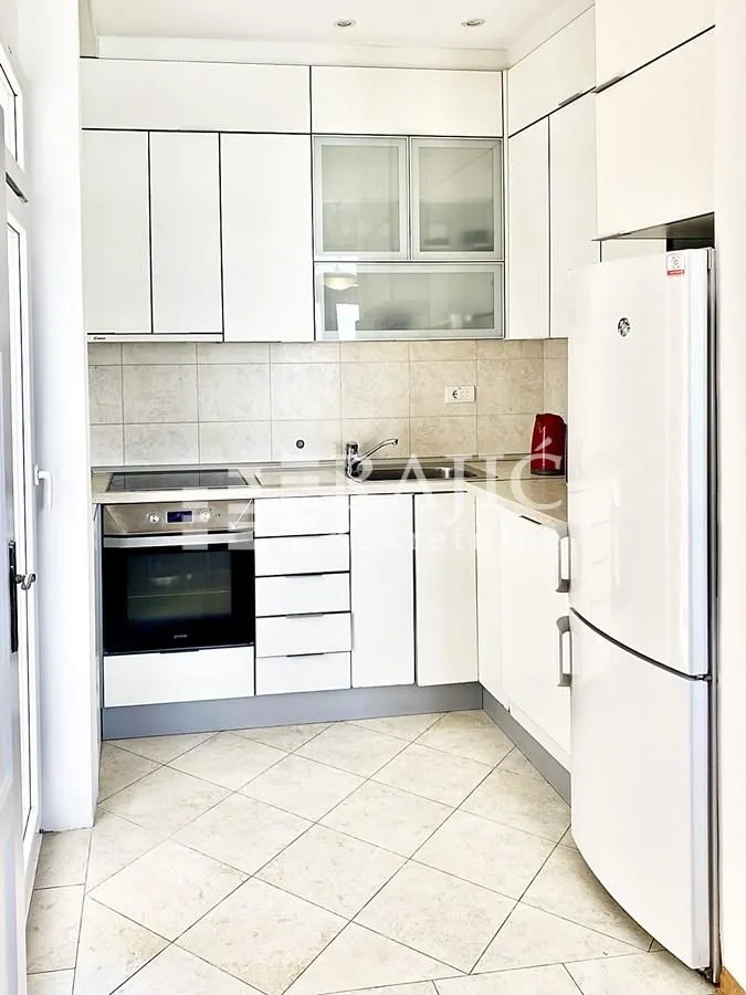 White kitchen with built-in appliances and a white refrigerator.