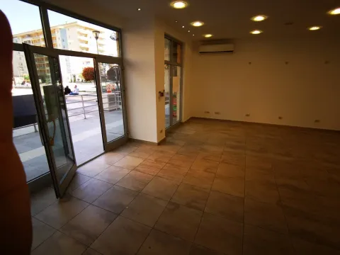 An empty commercial space with tiled flooring and large glass doors. - image 2