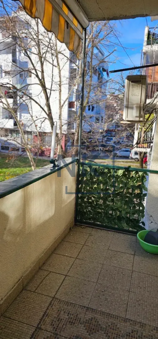 Natkriveni balkonski prostor sa pogledom na okolne zgrade i ulicu.