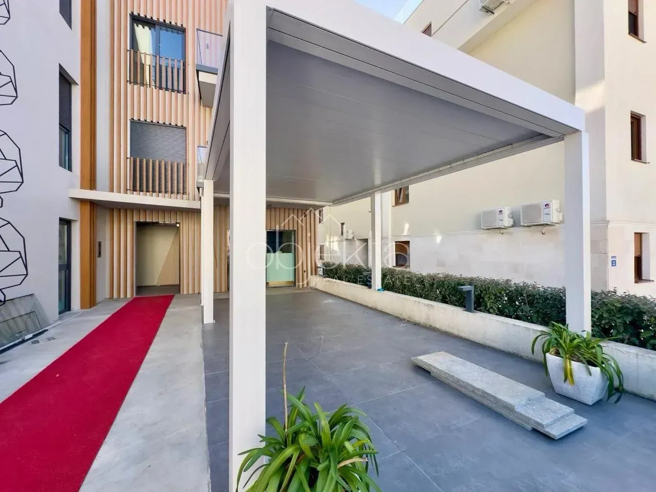 Covered parking space with a canopy in front of a modern building.