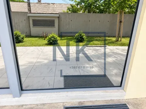 View through a glass door towards the paved yard and lawn. - image 5