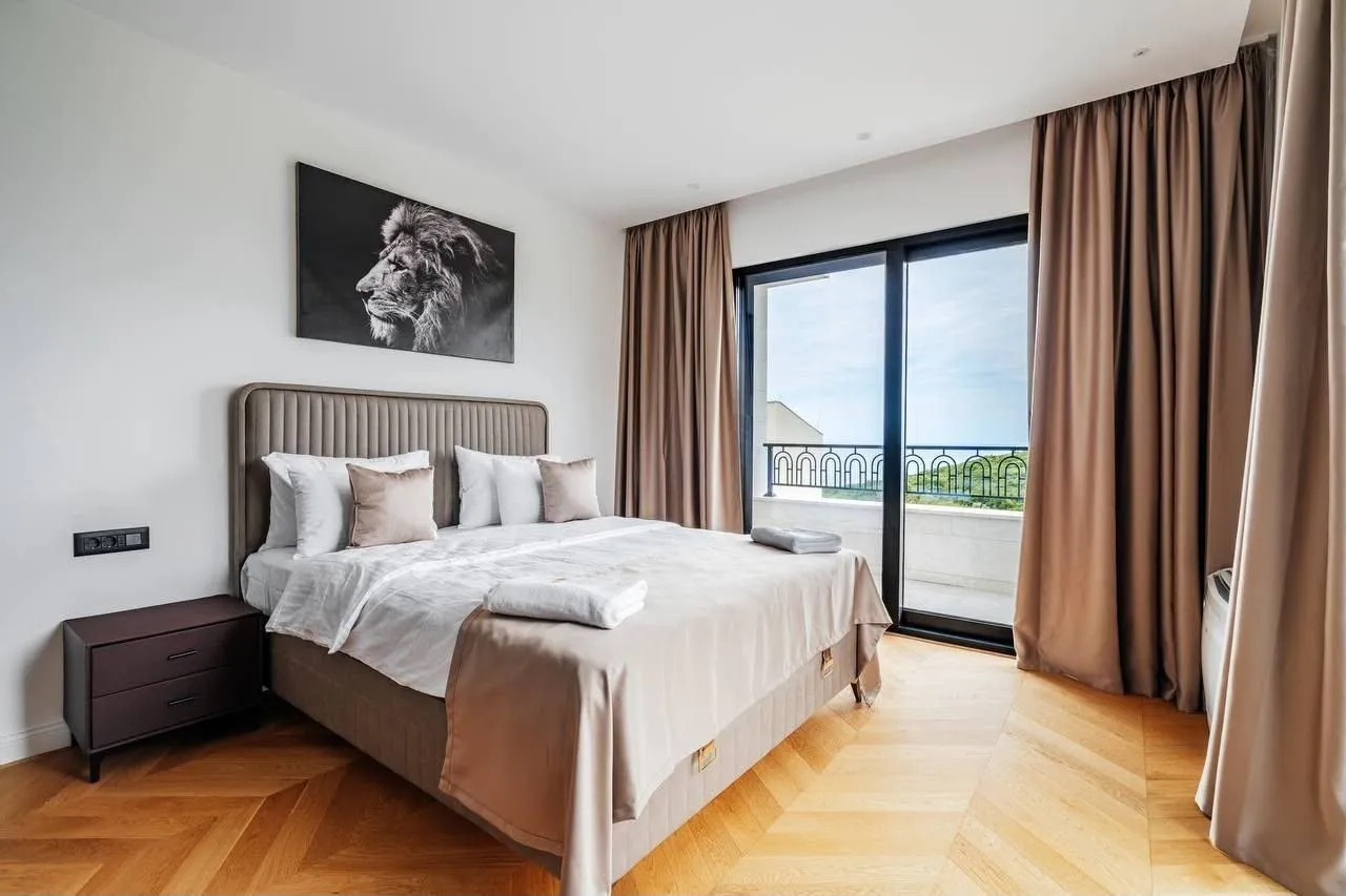 Modern bedroom with a double bed, wooden floor, and access to the terrace.