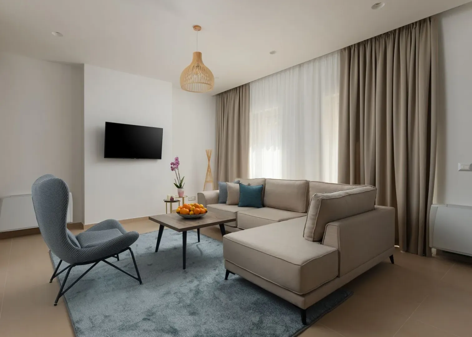 Modern living room with a sofa, armchair and wall-mounted TV.