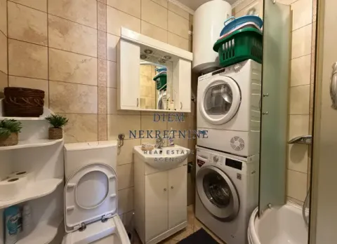 Compact bathroom with a sink, toilet, shower cabin, and stacked washing and drying machines. - image 6