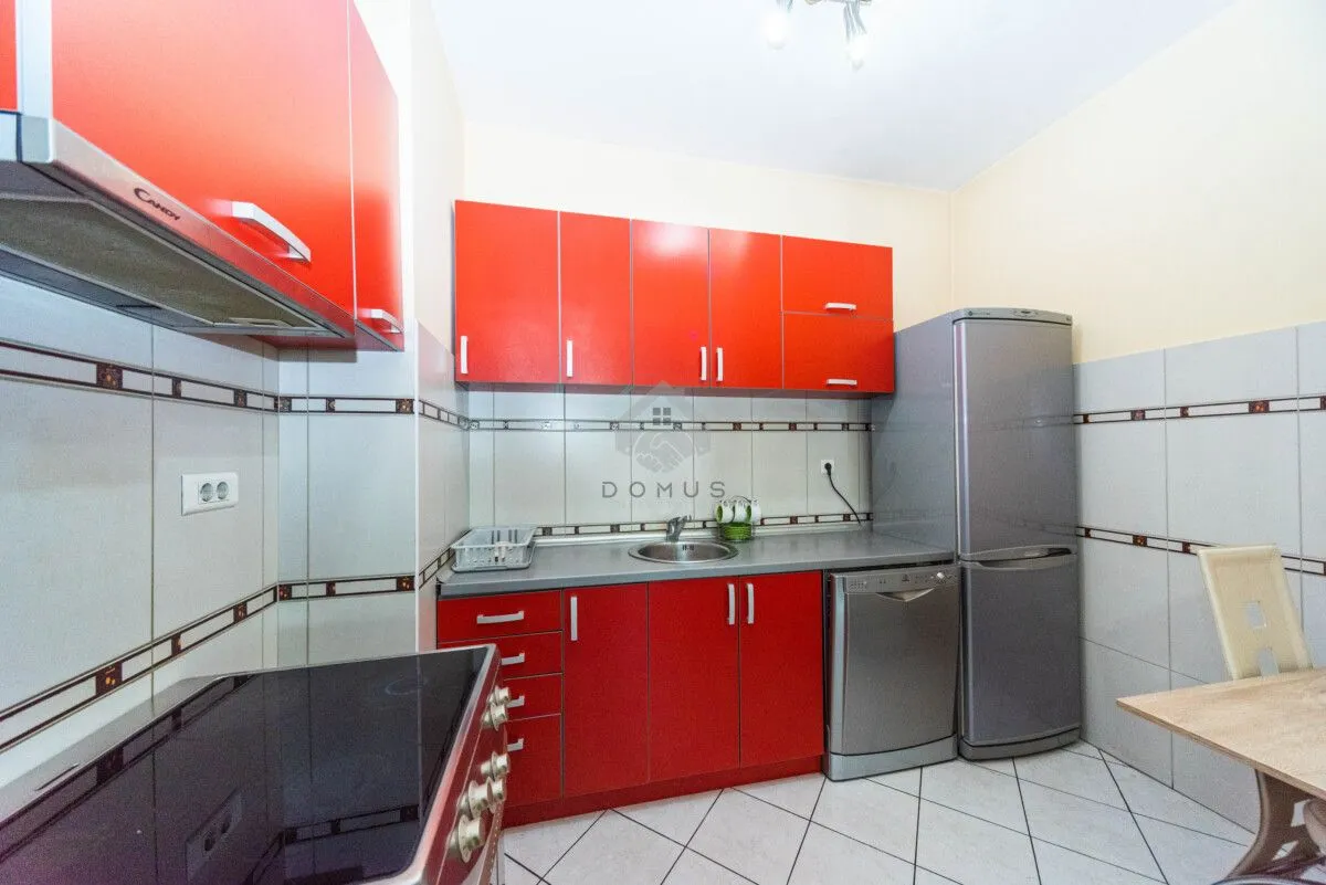 Kitchen with red cabinets, sink and built-in appliances.