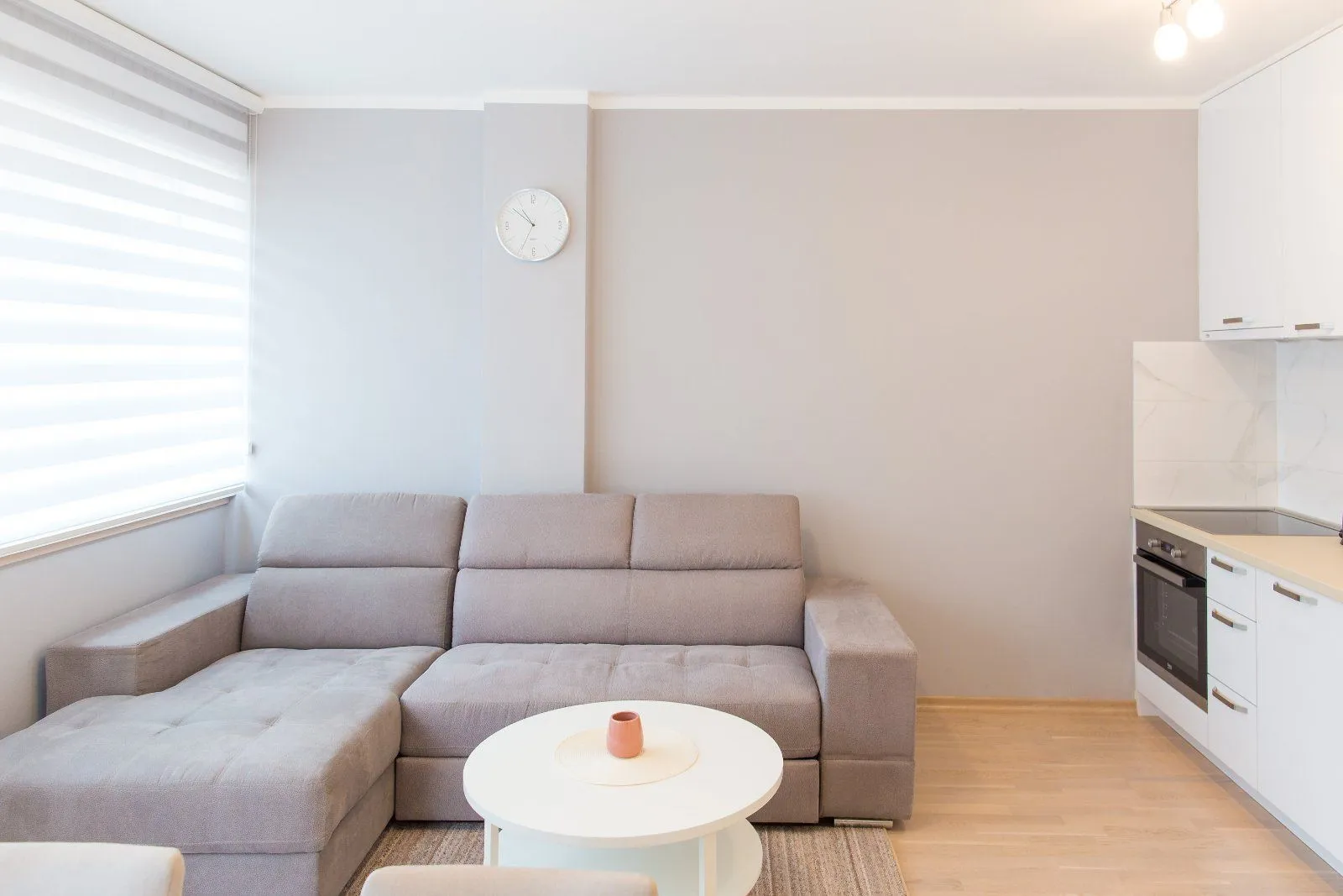 Living room with a sectional sofa and a small kitchen in the background.