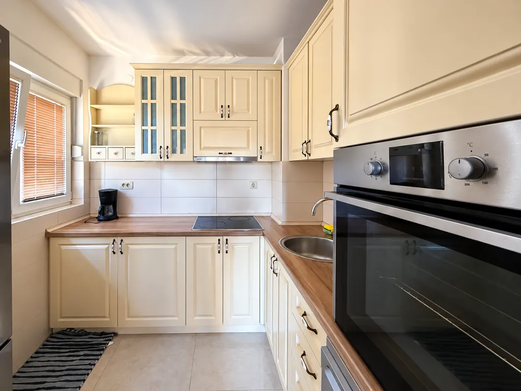 Kitchen with light cabinets and a built-in oven.