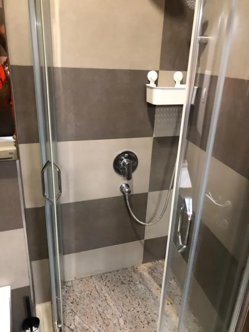 Modern shower cabin with glass partition and ceramic tiles.