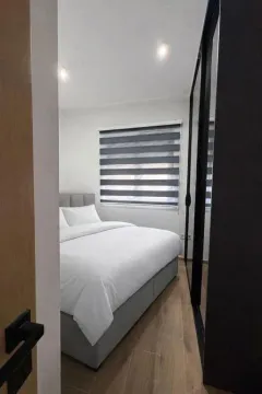 Pogled na moderno uređenu spavaću sobu sa bračnim krevetom i velikim ormarom. - image 10